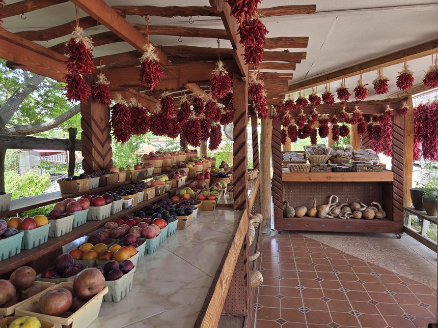 Chile ristras hanging above crates of fruit at a roadside stand