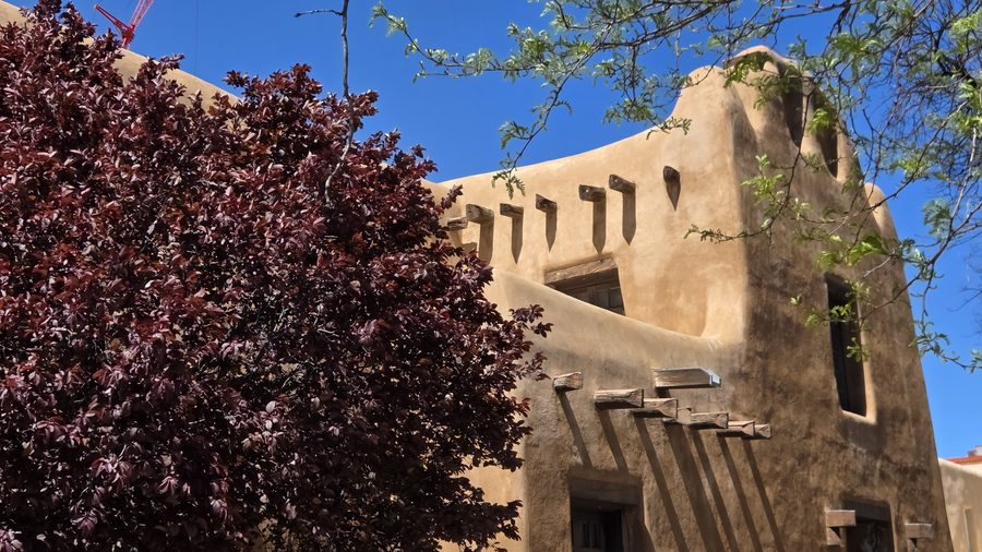 Adobe wall with projecting viga beams under a deep blue sky
